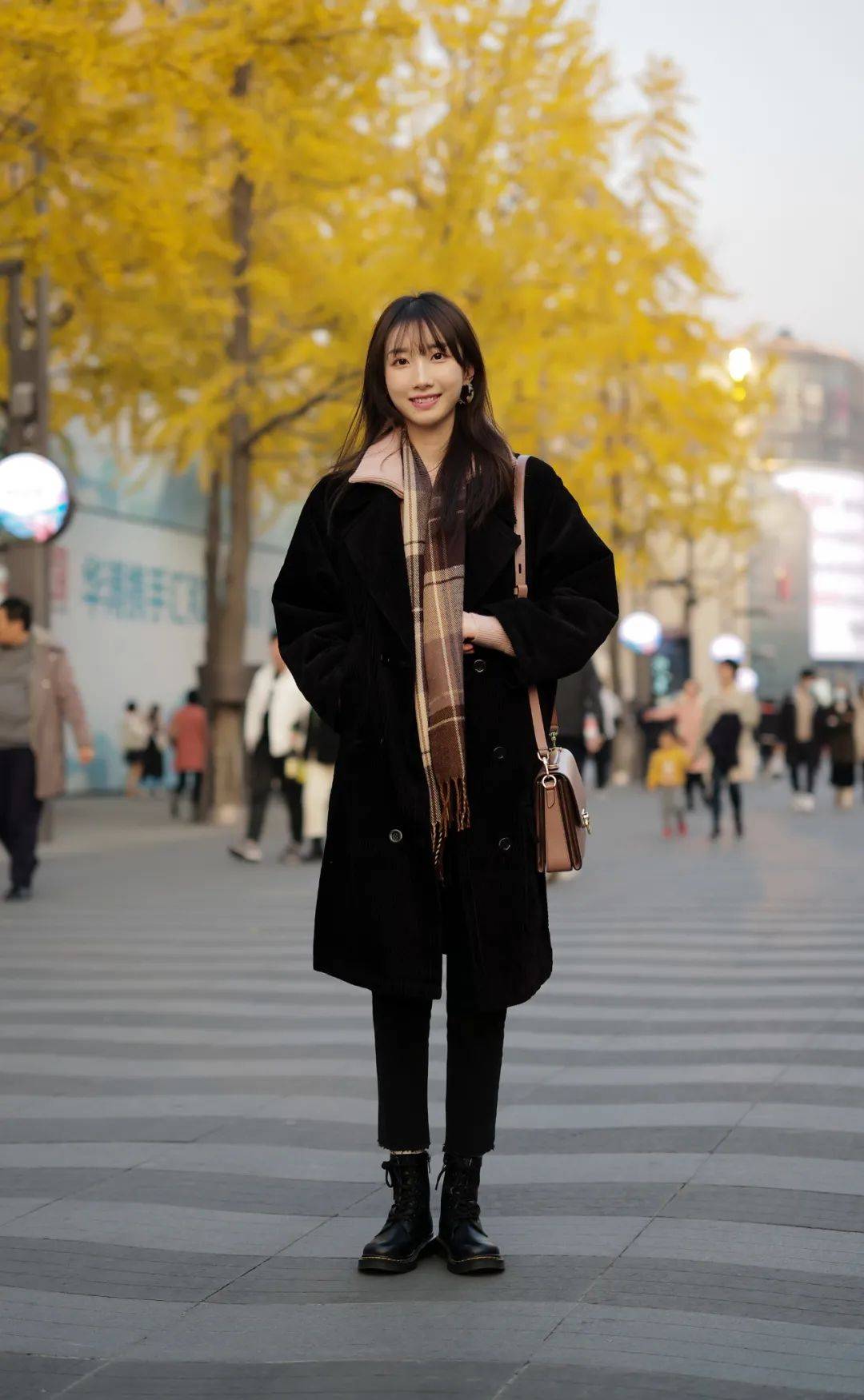 黑色长款大衣是冬日里必备的款式，用一条格纹围巾来点缀，一身黑也不单调。