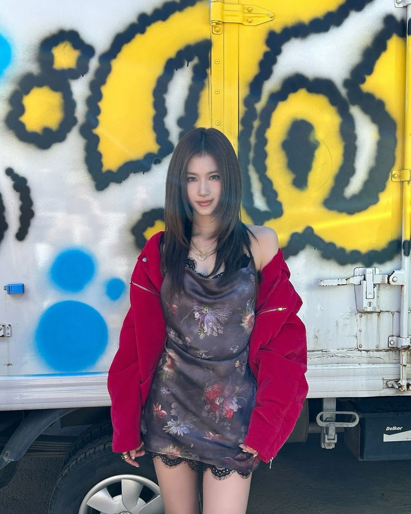 印花吊带短裙+黑色蕾丝边，外披红色工装外套，背景涂鸦墙明艳张扬的辣妹风