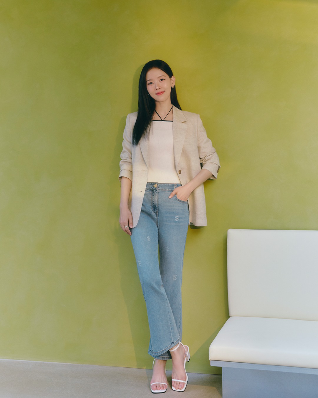 米色西装外套+白色吊带+浅蓝直筒牛仔裤，白色细带凉鞋，明黄墙面背景温柔知性干练