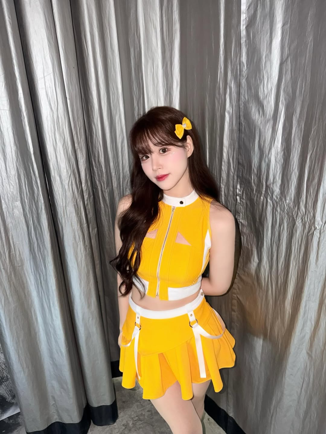 亮黄运动套装配百褶短裙，蝴蝶结发饰呼应，元气女团舞台感