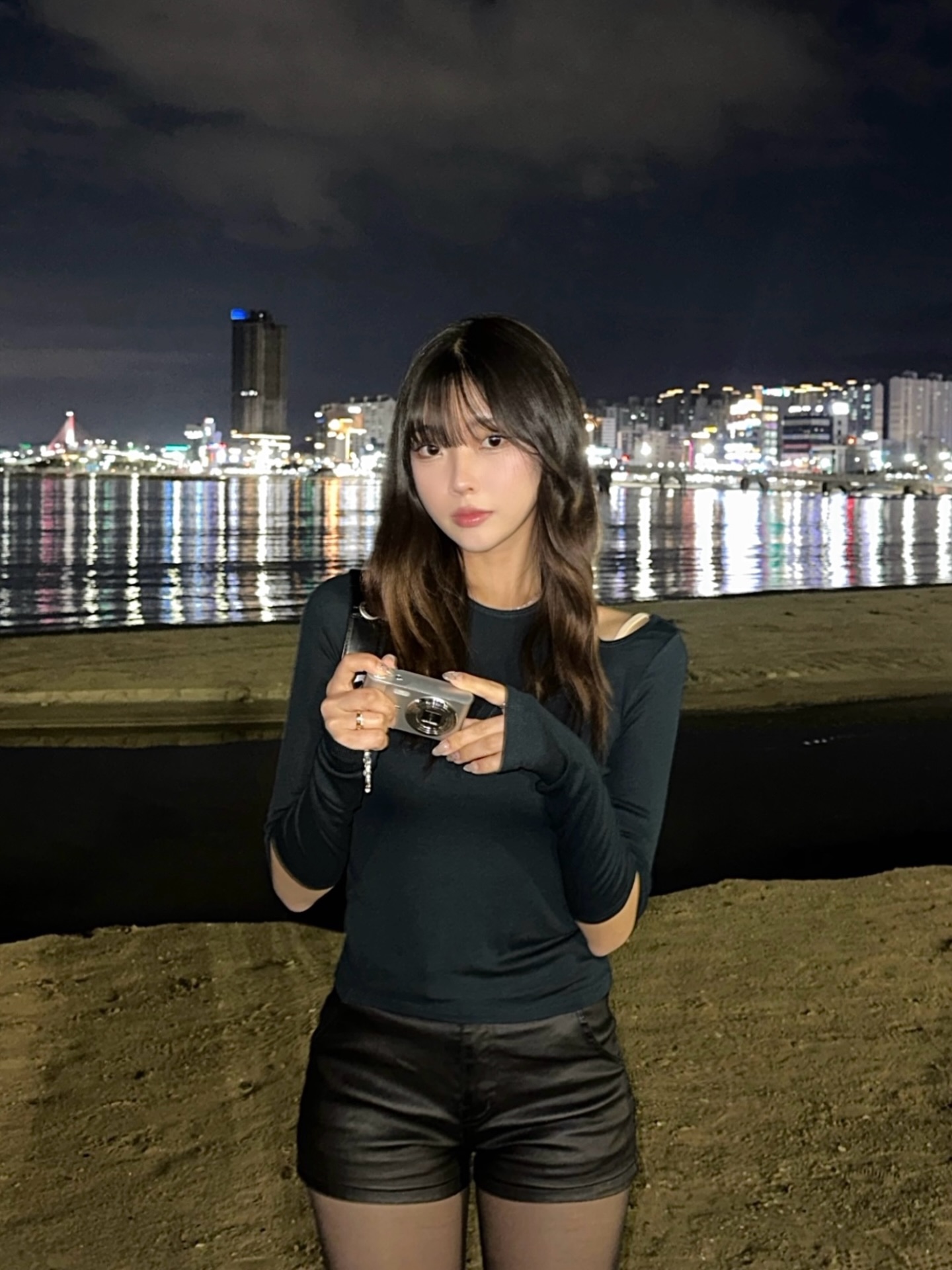 露肩黑色长袖配皮质短裤，手持相机江边夜景文艺都市夜晚酷感