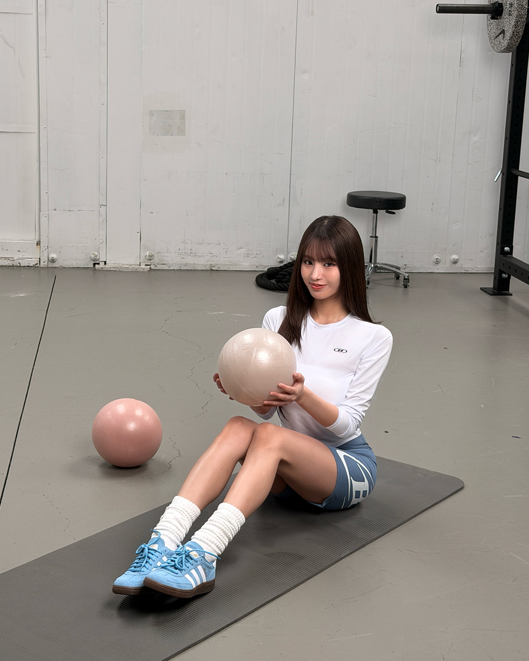 白色紧身长袖T恤搭配蓝色运动短裤与蓝色德训鞋