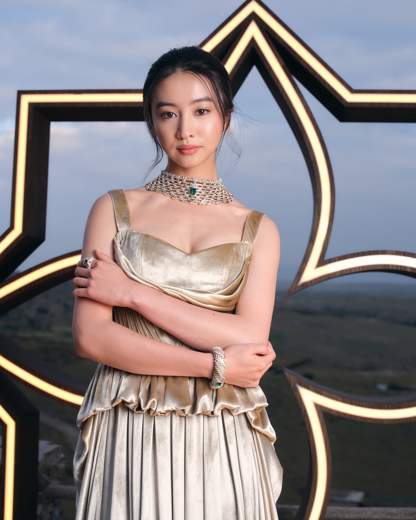香槟金吊带丝绒百褶长裙配祖母绿珠宝，黄昏艺术展奢华风